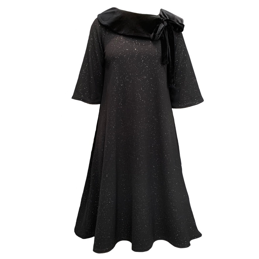 This is a midi length dress with flared sleeves and skirt. The main body of the dress is black with silver sparkles, and a contrasting black velour collar lays across the shoulders, tying into a bow on one side.