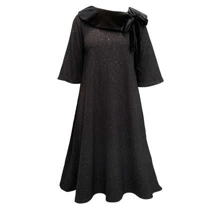 This is a midi length dress with flared sleeves and skirt. The main body of the dress is black with silver sparkles, and a contrasting black velour collar lays across the shoulders, tying into a bow on one side.