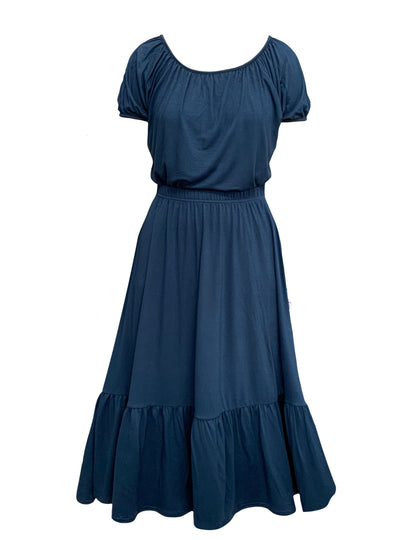 This is a french navy jersey skirt silhouetted against a white background. The skirt has a gathered elasticated waist and deep gathered hem frill. This is a front veiw and tucked in to the skirt is a top in the same colour. It is a loose shape and has short gathered sleeves.