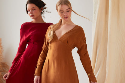 Two women are standing next to each other in a Sarvin Mustard long sleeve Midi Dress.