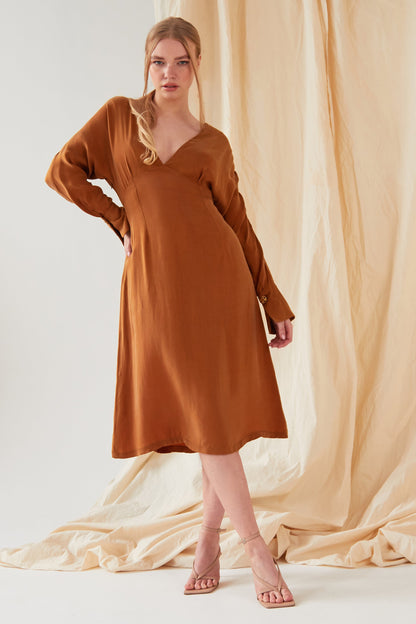 The model is wearing a Sarvin Mustard long sleeve Midi Dress.