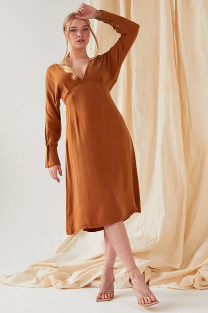 The model is wearing a Sarvin Mustard long sleeve Midi Dress.