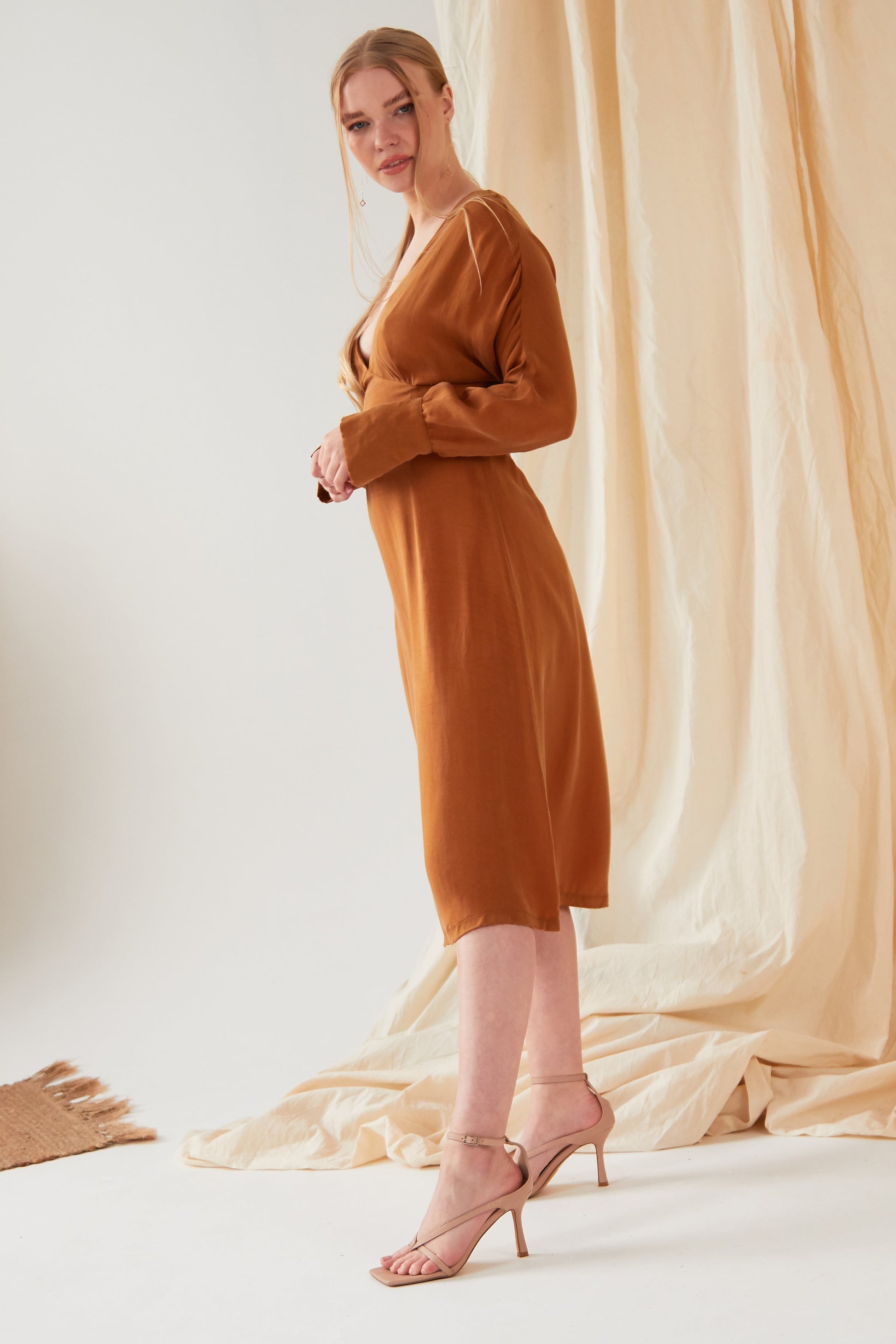 The model is wearing a Sarvin Mustard long sleeve Midi Dress.