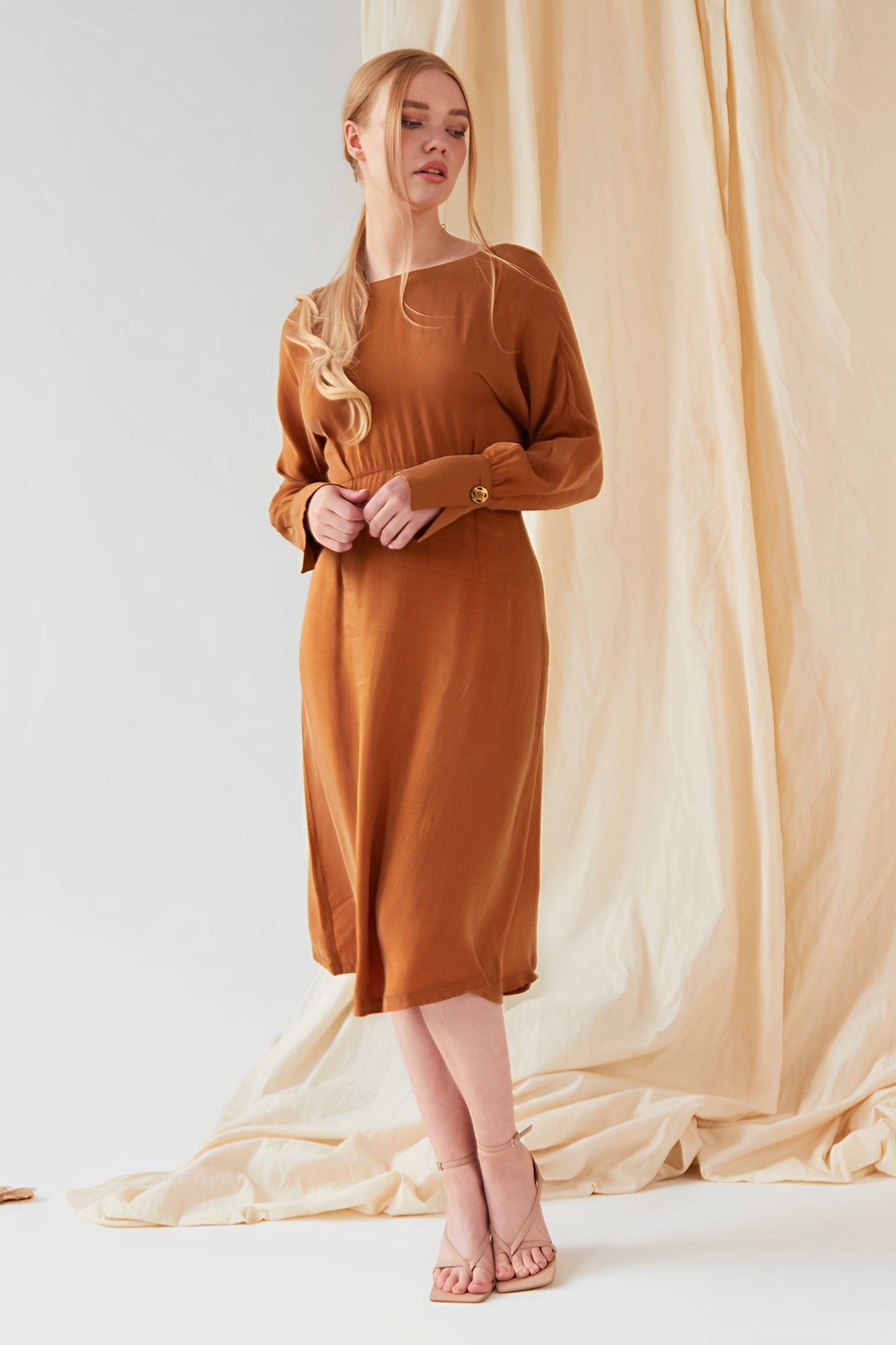 The model is wearing a Mustard long sleeve Midi Dress by Sarvin.