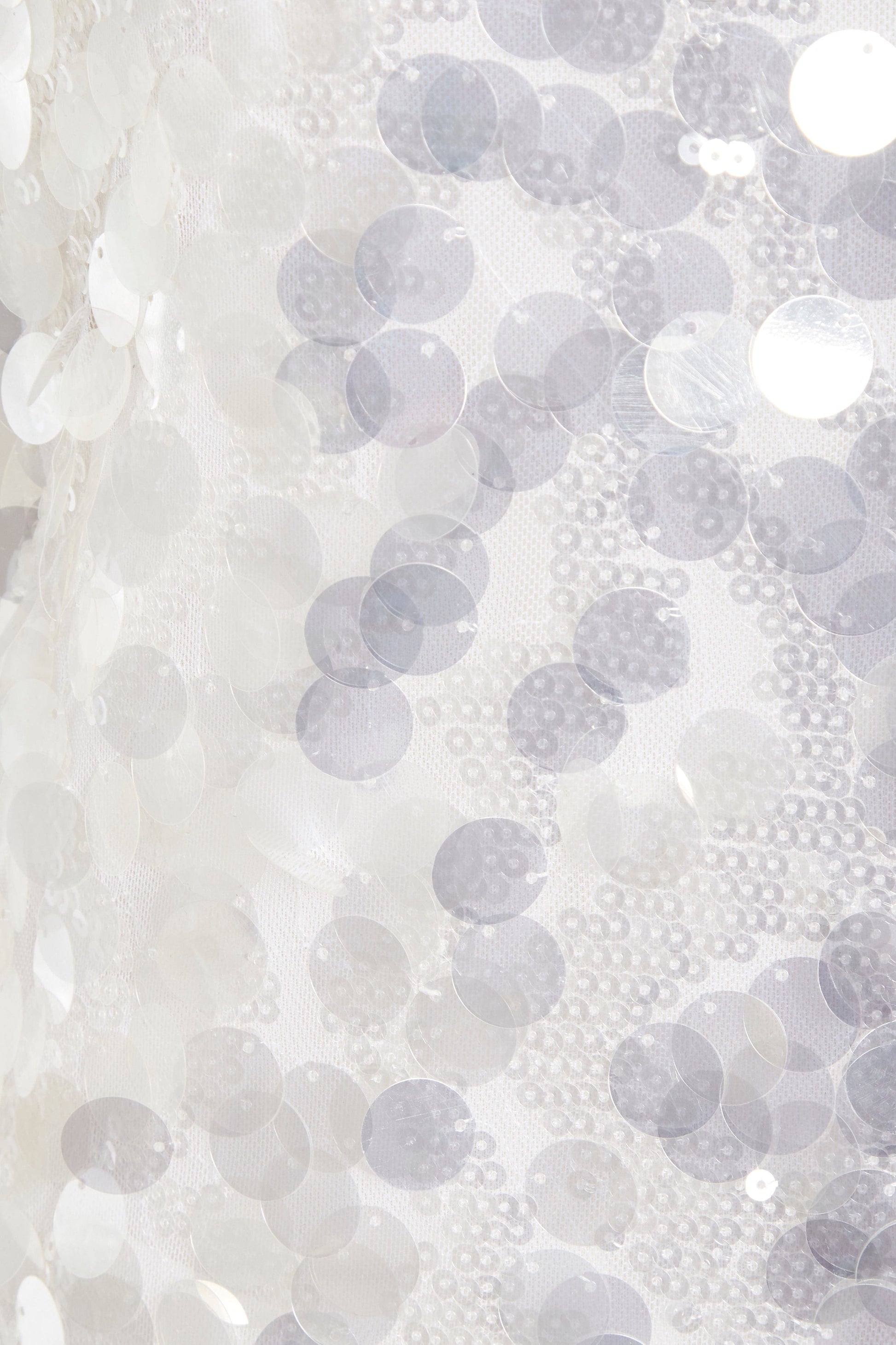 A close up of a Sarvin white backless mini dress with sequins on it.